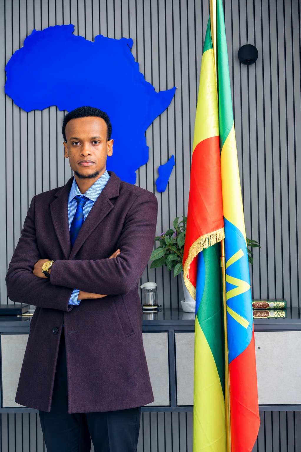 Yahya Abdella standing beside the Ethiopian flag and a blue map of Africa